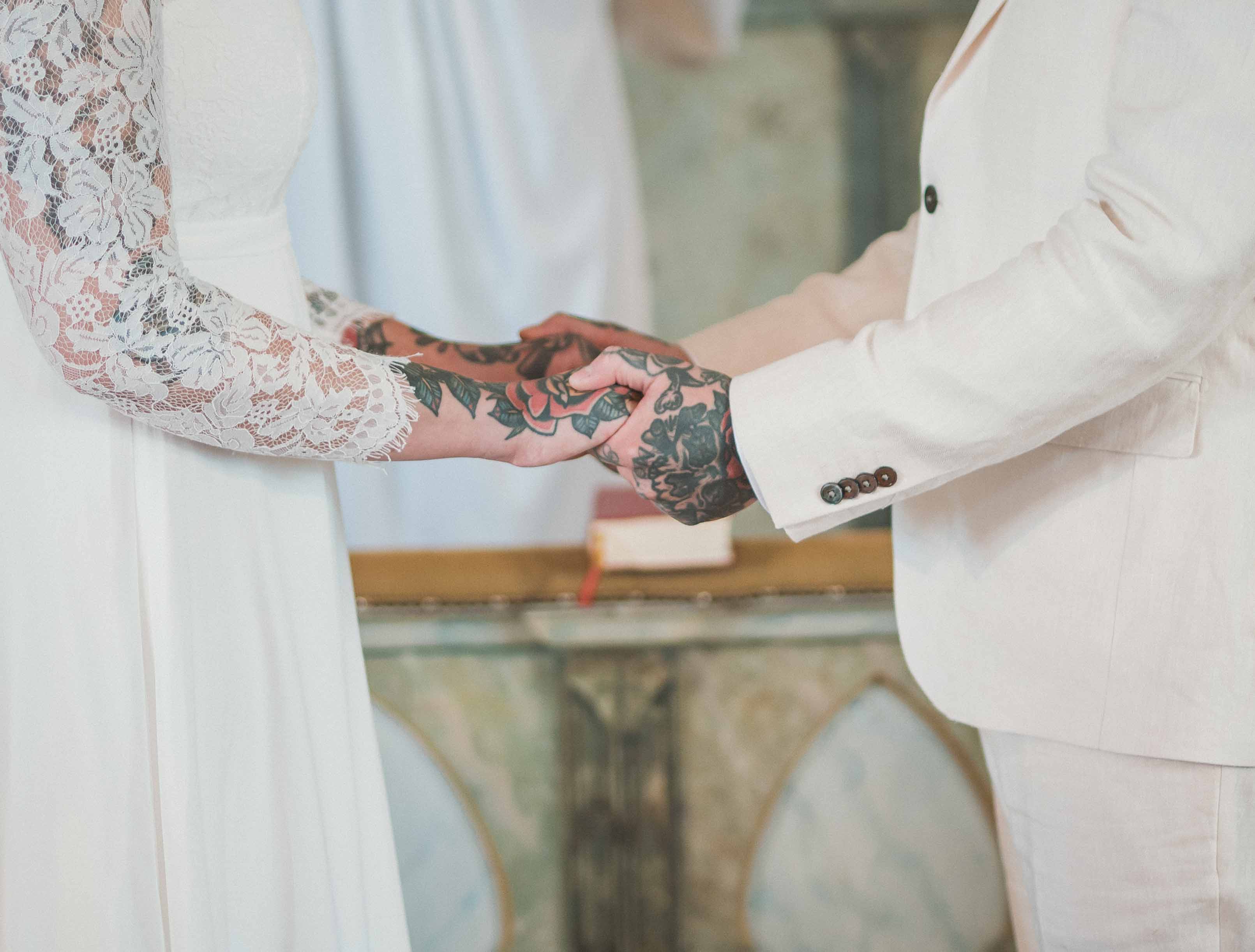 Rebecka och Aron håller varandras tatuerade händer under vigseln