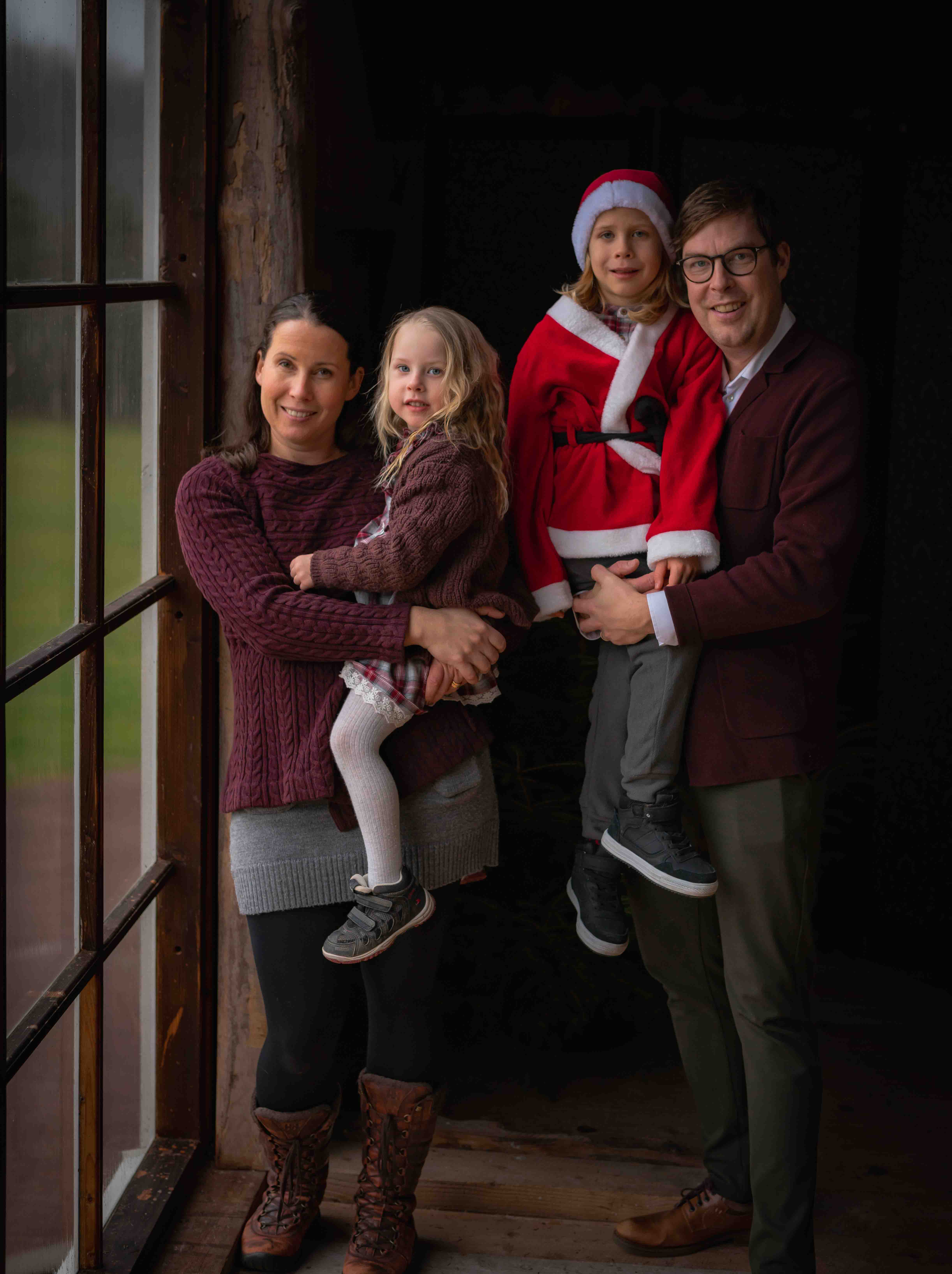Familj fotograferad vid ett stort fönster på Eventladan i Romelanda