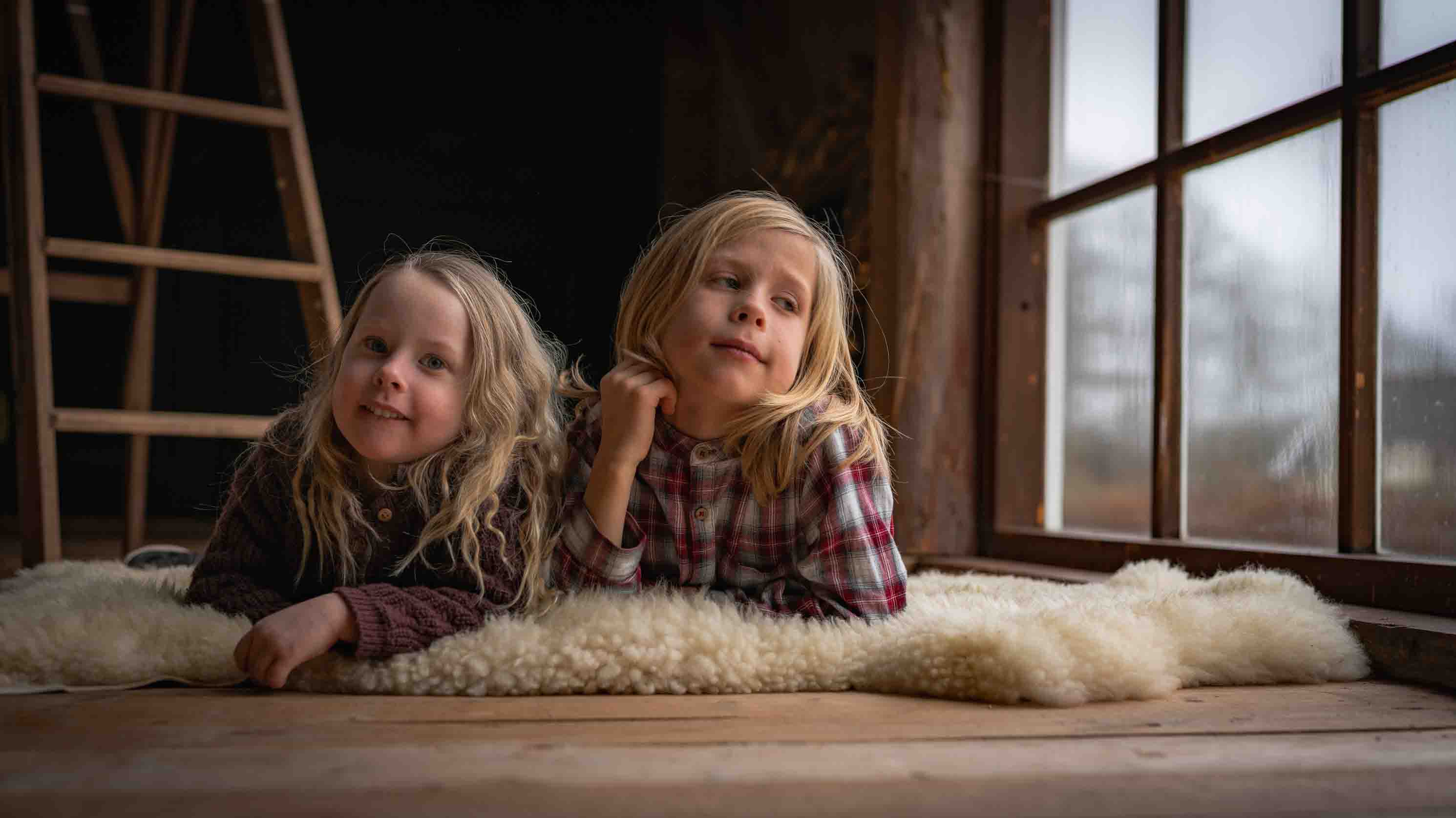 Två syskon fotograferade tillsammans vid ett fönster